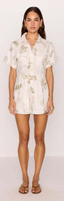 Model wearing a White & Sage Leaf Print Playsuit featuring short sleeves and a collared neckline.