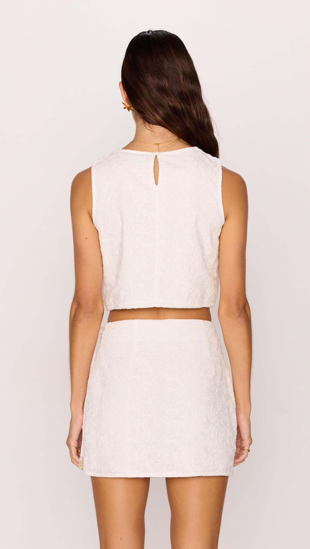 Back view of a model wearing the White Wrap Mini Skirt paired with a matching sleeveless top.