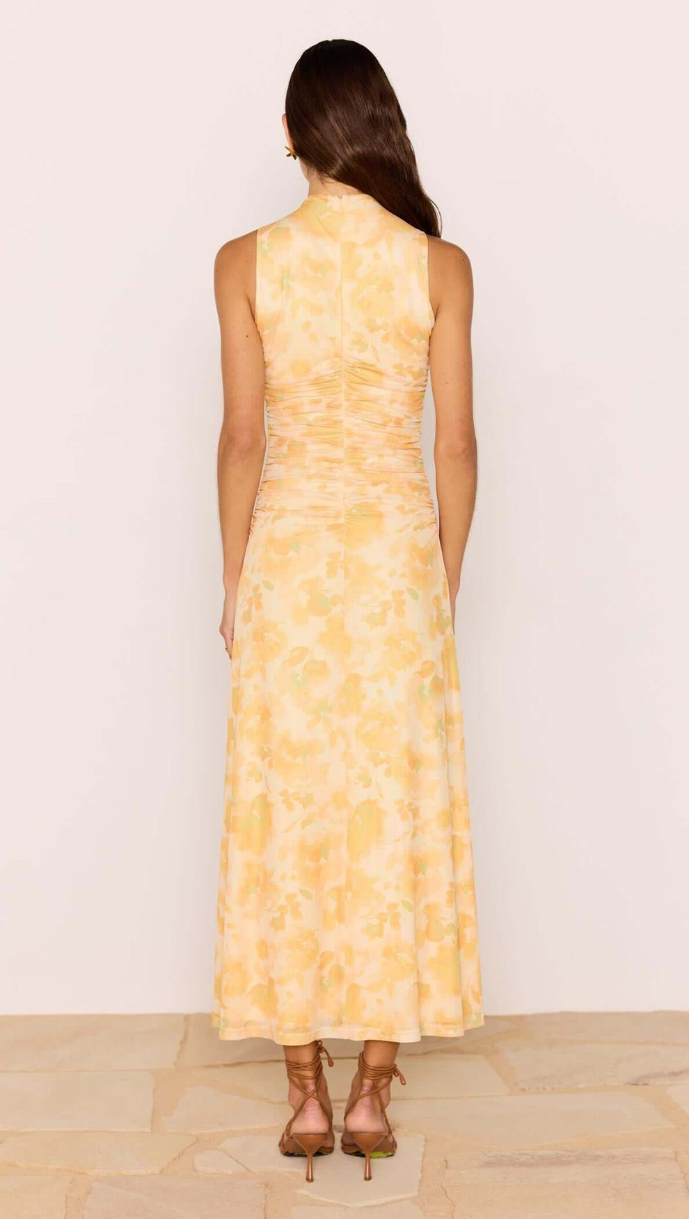 Back view of a woman wearing a Yellow Floral Mesh Midi Dress showcasing a soft floral pattern and fitted bodice.