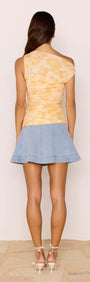 Back view of a model wearing the Yellow Floral Mesh Top with a blue skirt, perfect for summer outings.