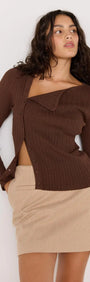 Model wearing brown ribbed cardigan with an open wrap design and beige mini skirt, showcasing a stylish outfit.