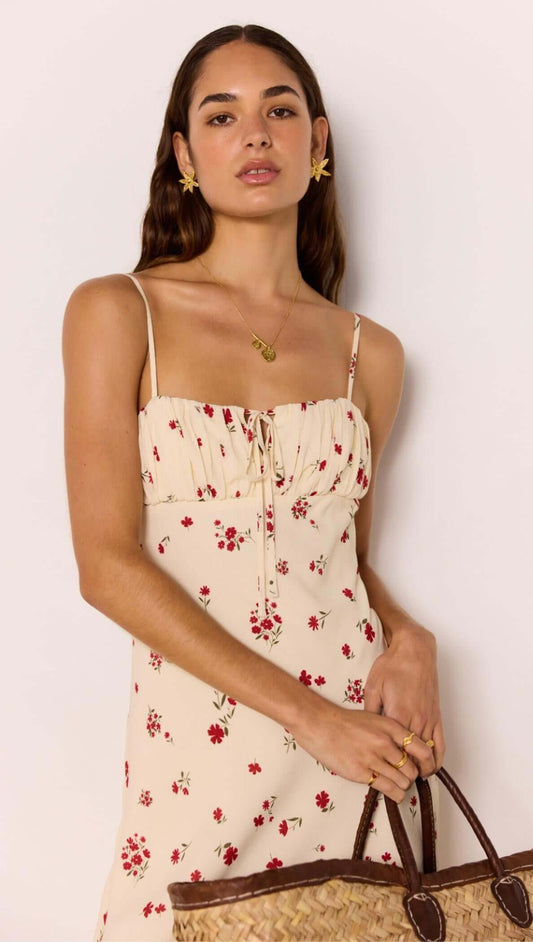 Red & Cream Floral Bias Midi Dress worn by model with floral pattern and spaghetti straps, holding a woven bag.