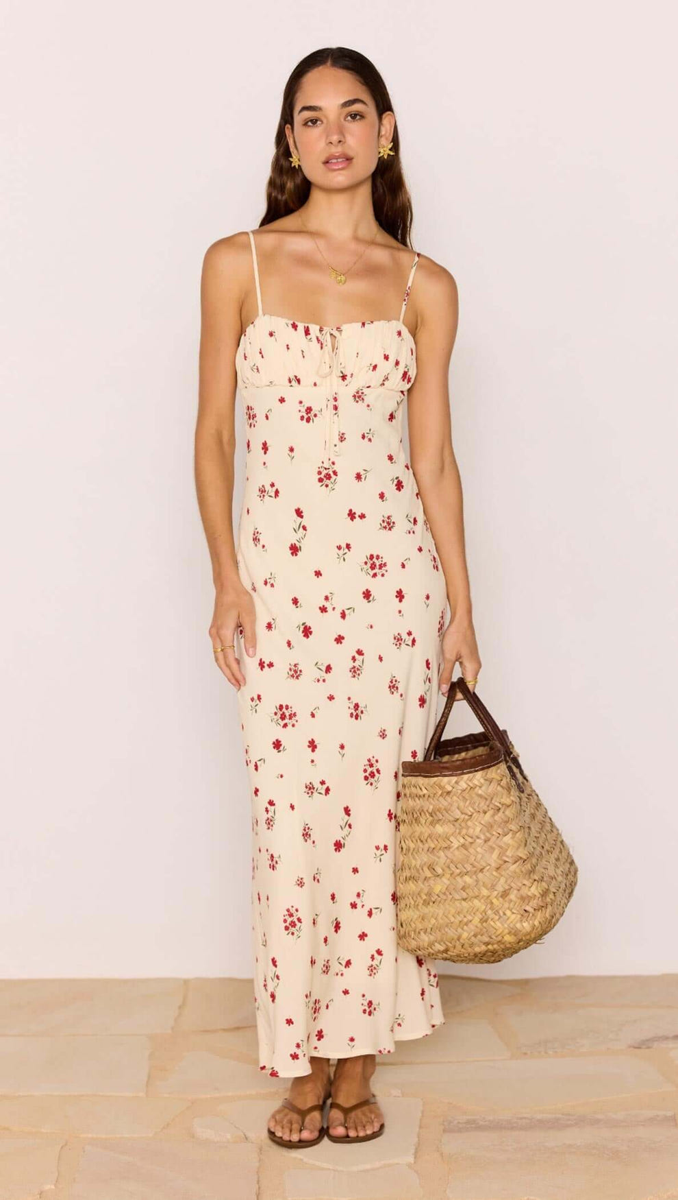 Model wearing a Red & Cream Floral Bias Midi Dress with a woven bag, showcasing a romantic summer look.