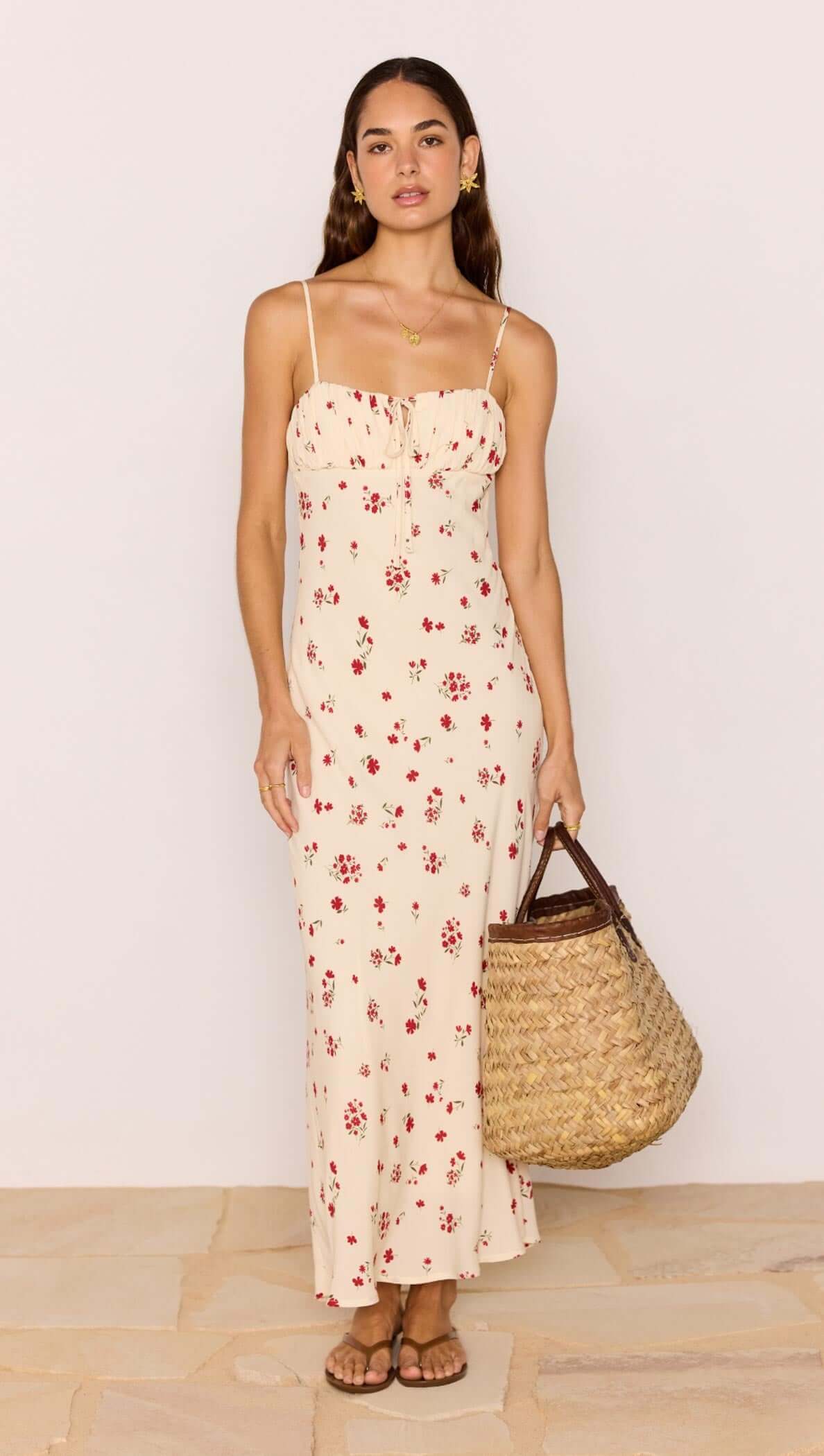 Model wearing a Red &amp; Cream Floral Bias Midi Dress with a woven bag, showcasing a romantic summer look.