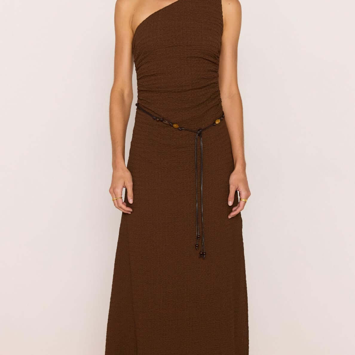 One-Shoulder Brown Midi Dress with Beaded Belt on model in chocolate brown with a ruched bodice and side split.