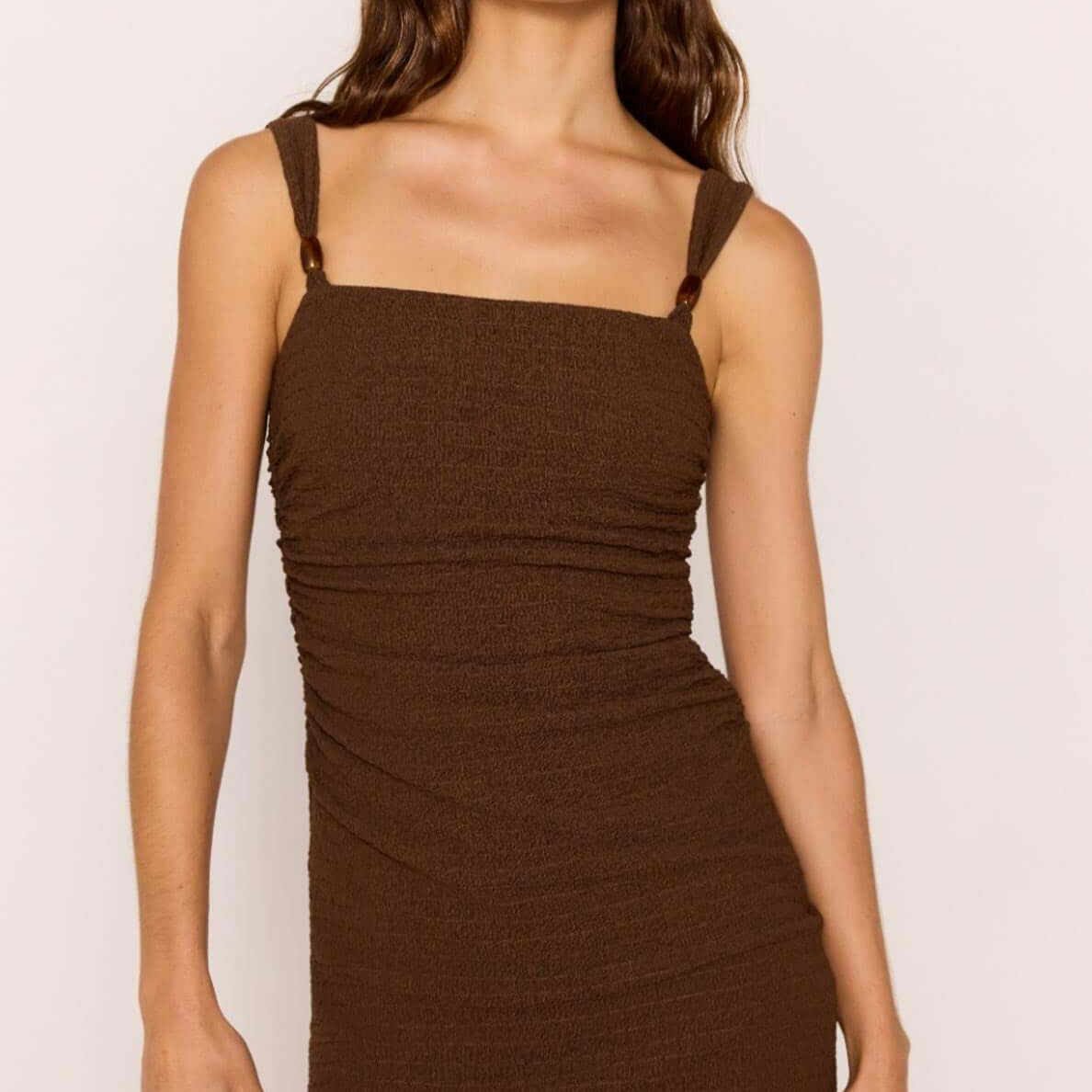 Brown Ruched Mini Dress with Bead Detail modeled by a woman, highlighting the square neckline and ruched design.