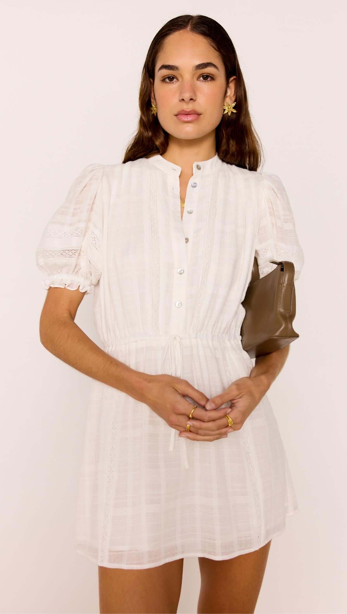 A model wearing the Lace Detail White Cotton Mini Dress with puff sleeves and lace details, styled with a chic handbag.