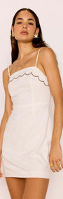 Model wearing a Scallop Edge Cotton White Mini Dress with a scalloped neckline and slim adjustable straps.