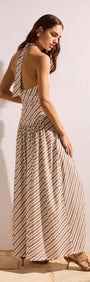 Back view of a model wearing the Brown & Cream Stripe Low-Waist Halter Maxi Dress, showcasing its flowy design and striped pattern.