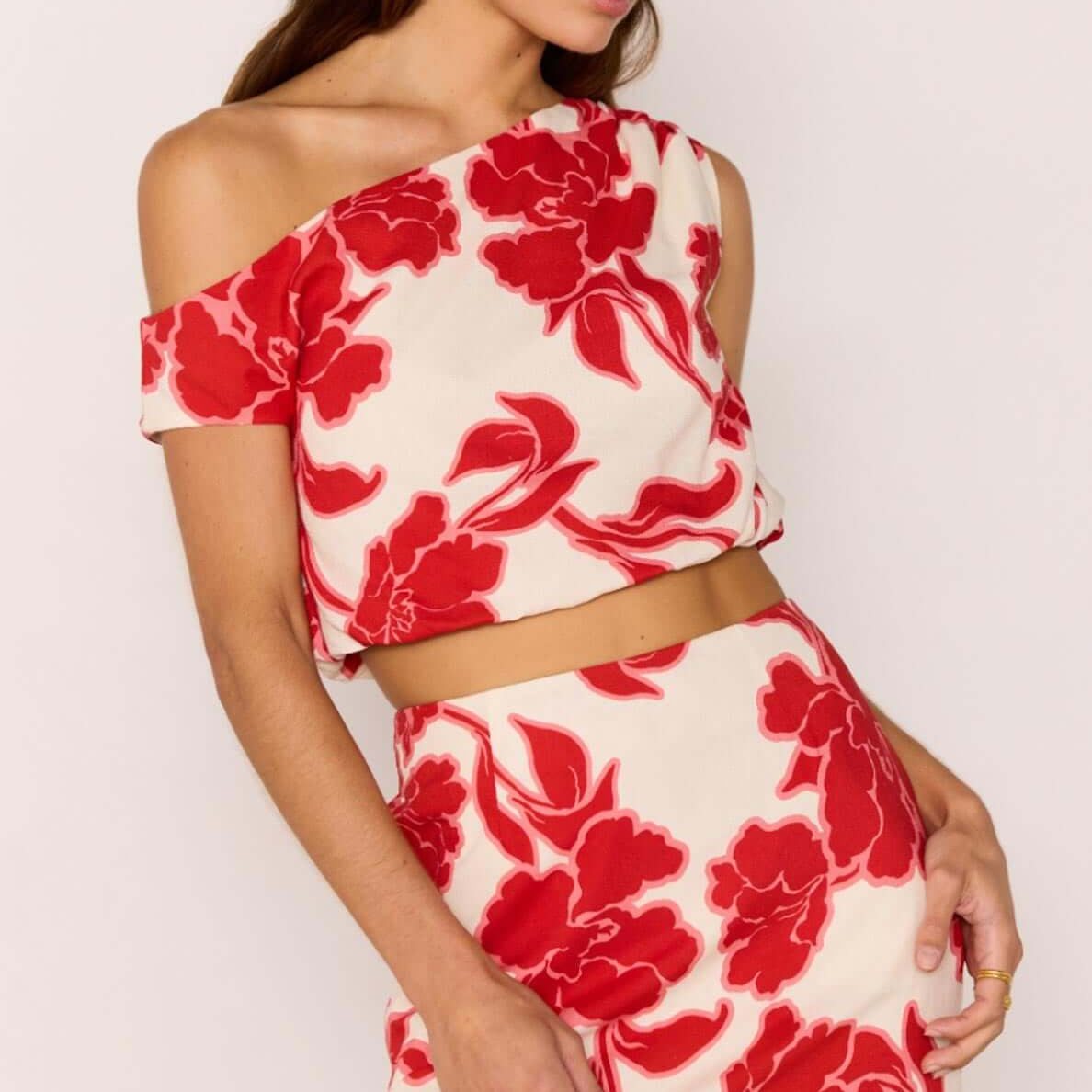 Red & White Floral Linen Blend Asymmetric Crop Top stylishly paired with a mini skirt, perfect for summer events.