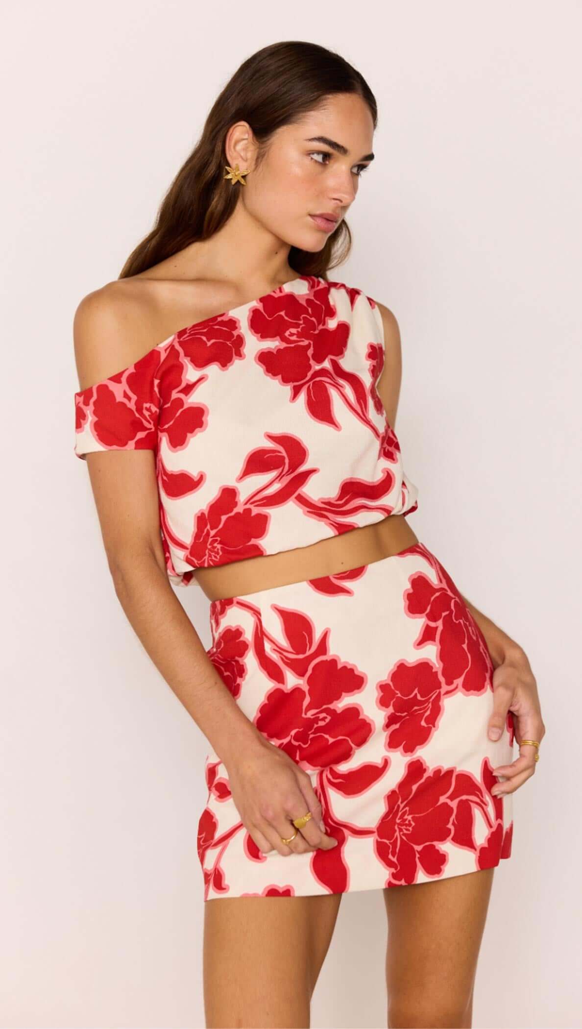 Red & White Floral Linen Blend Asymmetric Crop Top stylishly paired with a mini skirt, perfect for summer events.
