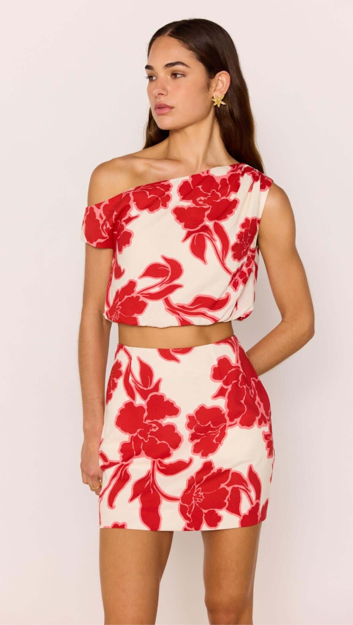 Red &amp; White Floral Linen Blend Asymmetric Crop Top worn with matching skirt, showcasing bold floral print and stylish design.