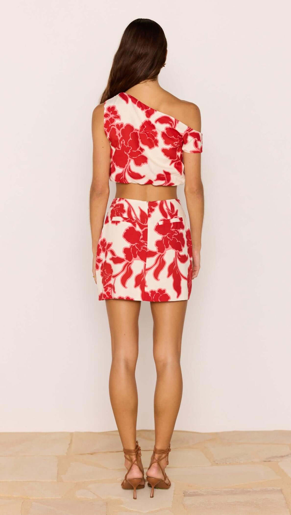 Back view of a model wearing a Red & White Floral Linen Blend Mini Skirt paired with a matching top.