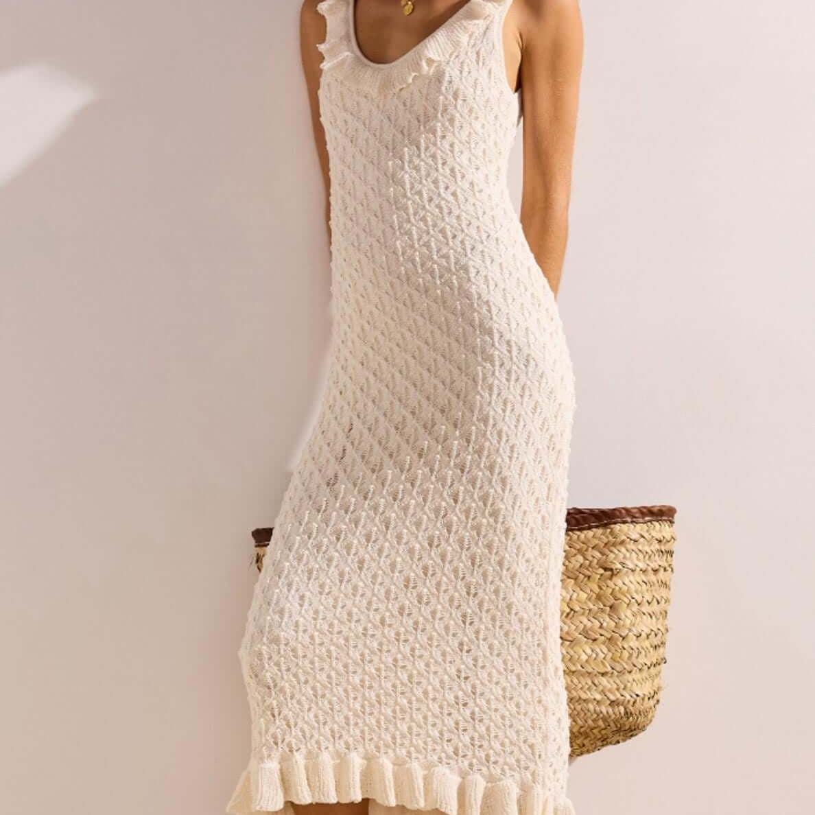 Model wearing a White Pointelle Knit Midi Dress with a ruffled hem, complemented by a woven bag.