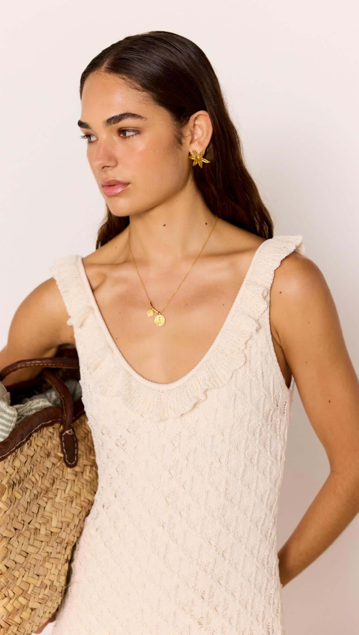 Model wearing a White Pointelle Knit Midi Dress, featuring a scoop neckline and ruffled hem, with beach accessories.